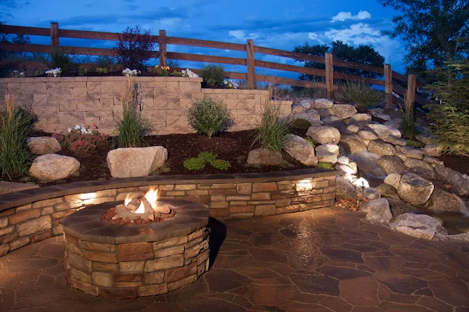 Custom fire pit with stone seating wall at night